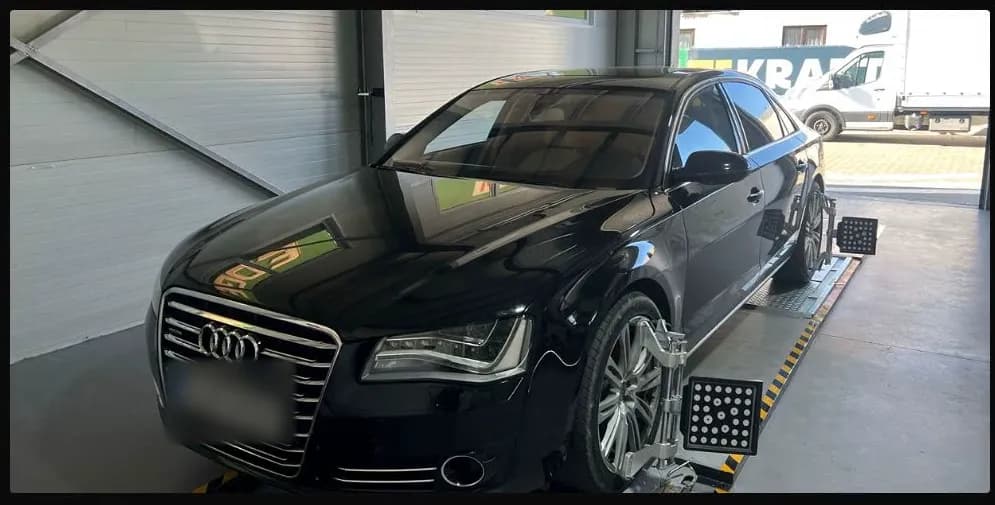Audi negru pe standul de geometrie, cu senzorii montați pe roți